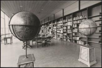 View of a library room with two globes on a pedestal in the foreground
