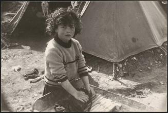 A young girl washes an item of clothing on  a washboard in a refugee camp after the destruction of the Belice earthquake in Sicily 1968