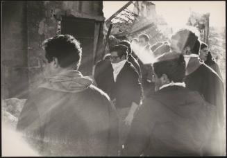 A crowd of men look onto collapsed building in the aftermath of the Belice earthquake, 1968, Sicily