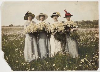 Four women wearing hats and holding daisies