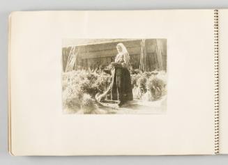 [Woman in headscarf standing with yarn and needles among sheaves of grain, page 32 of The Doukhobors I album]