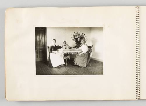 [Three women sitting at dining table with large bouquet of flowers, page 38 of The Doukhobors I album]
