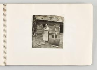 [Woman standing in yard and holding bundle of straw, page 31 of The Doukhobors I album