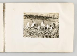 [Women and children sitting on farmland with backs turned, page 23 of The Doukhobors I album]