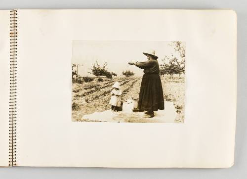 [Woman letting grain sift through her fingers, with child beneath her, page 19 of The Doukhobors I album]
