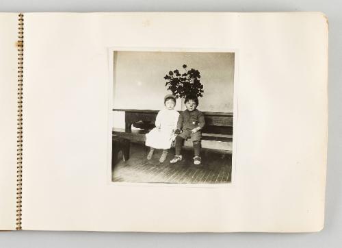 [Boy and girl sitting on bench in front of planter, page 13 of The Doukhobors I album]