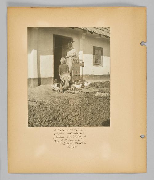 A Galician mother and children with their pet chickens in the doorway of their little home at Kildrum, Manitoba Canada [Page 6 of New Canadians album]
