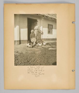 A Galician mother and children with their pet chickens in the doorway of their little home at Kildrum, Manitoba Canada [Page 6 of New Canadians album]
