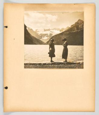 [Two women stand together at the shore of Lake Louise] [Page 21 of Banff, Lake Louise album]