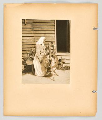 [Woman sitting on bench beside doorway with her spinning wheel] [Page 30 of The Doukhobors II album]