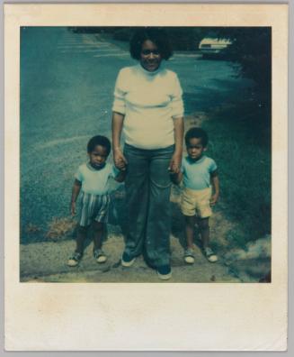 [Woman holding two little boys by the hand, both wearing high-waisted shorts]
