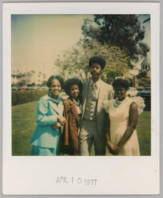 April 10, 1977 [Three women and man posing outdoors, woman on far left wearing bright blue blazer and matching skirt]