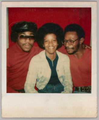 [Three people sitting together in front of red curtain]
