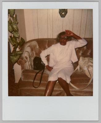 [Older woman wearing cat-eye glasses posing on velvet couch]
