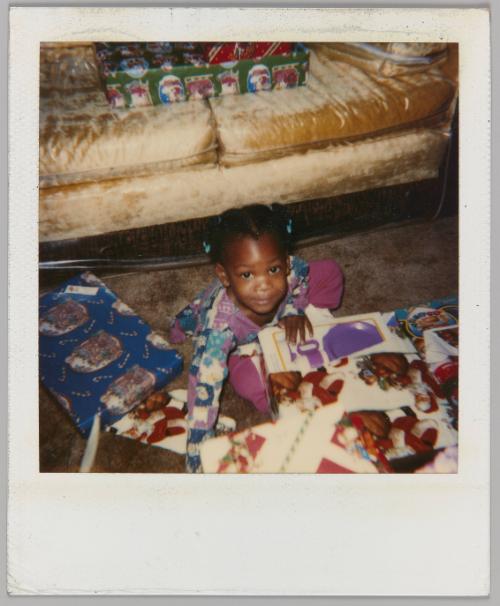[Little girl opening presents on ground beside couch]
