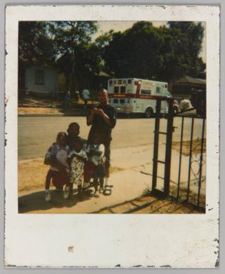 [Two men and three children with ambulance on road]
