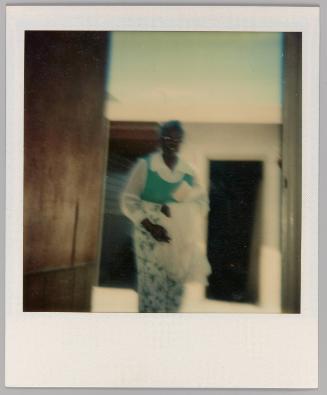 [Woman walking into room from outside holding white sheet]
