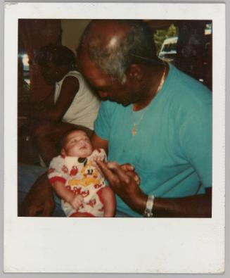 [Man holding newborn baby, baby grasping man's finger with hand]
