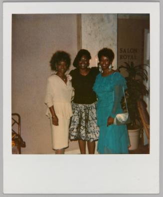 [Three women in cocktail dresses posing in hallway, 'Salon Royal' written on wall in background]
