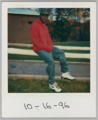 [Man wearing Nike sneakers sitting on fence]
