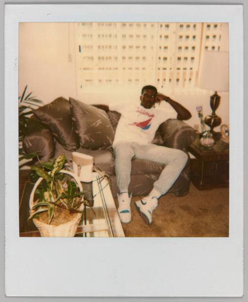 [Man wearing Nike shoes sitting in living room with plants]
