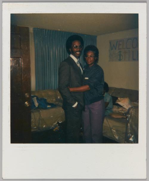 [Man and woman embracing in living room with Welcome Home sign]

