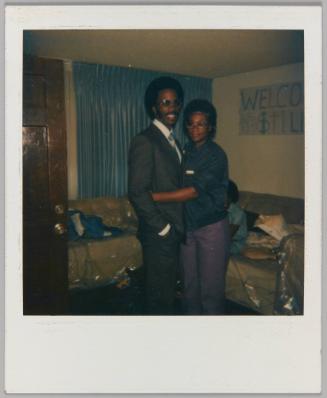 [Man and woman embracing in living room with Welcome Home sign]
