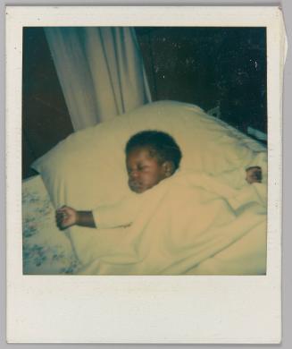 [Close-up of baby covered in blanket with arms open laying in bed]
