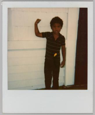 [Young boy flexing biceps in front of white wall]
