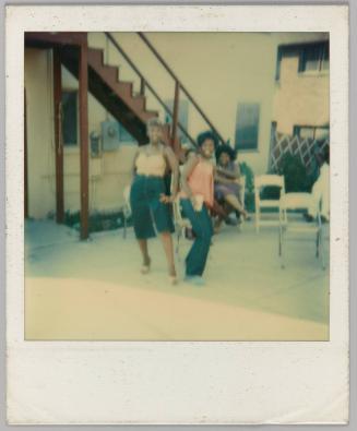 [Two women posing outside with folding chairs]
