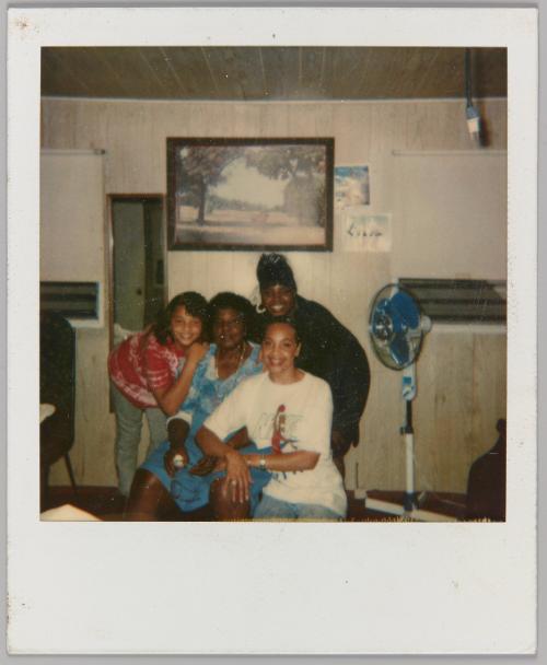 [Three adolescent women posing around older woman in home]
