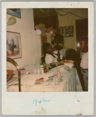 [Woman holding baby at a party with balloons]
