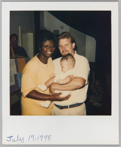 July 19, 1998 [Woman and man embracing while holding toddler in arms]