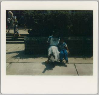 [Woman in blue and white sundress sitting on folding chairs with boy]
