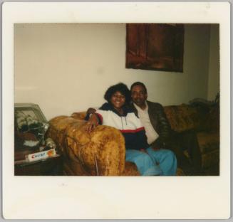 [Woman and man seated on yellow velvet couch]
