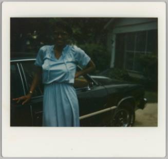 [Woman in blue sundress posing with car]
