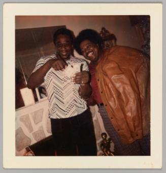 [Two men smile for the camera, holding two American bills]
