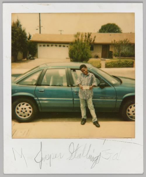 Jasper Stallings [Boy holding  document in front of turquoise car]
