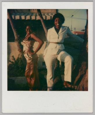 [2 women posing in white and pink silk suit on front lawn]
