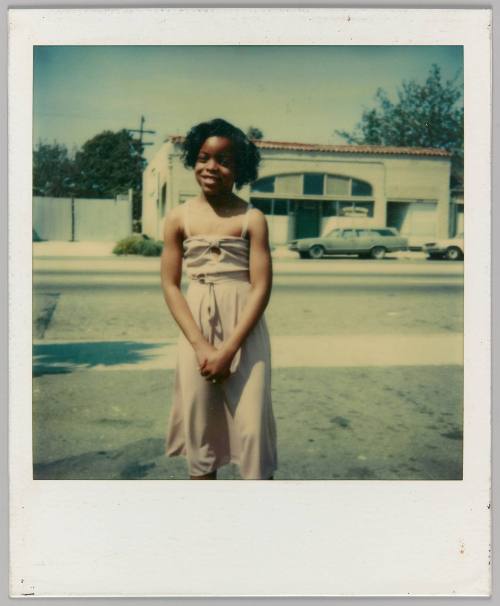 [Young girl in light pink dress smiling with hands clasped]
