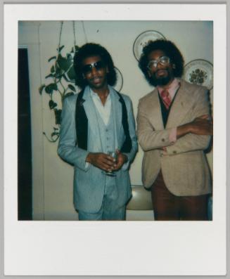 [Two men posing in suits and glasses]
