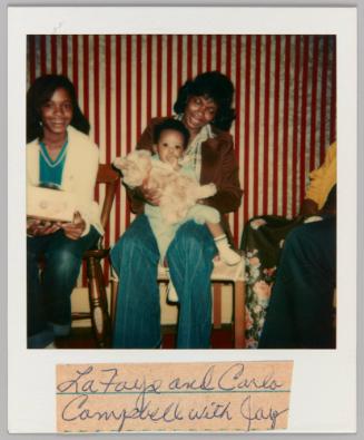Lafaye and Carlo Campbell with Jay [Woman holding toddler in lap with plush toy]
