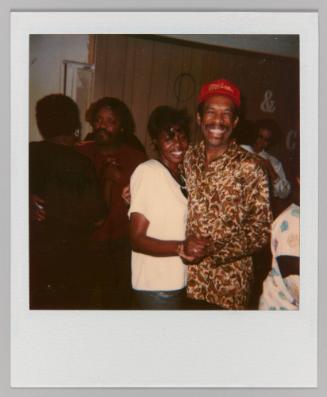 [Man and woman holding hands and smiling; man in paisley patterned shirt]
