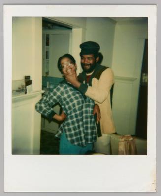 [Man in black hat squeezing womans' cheeks and smiling] 
