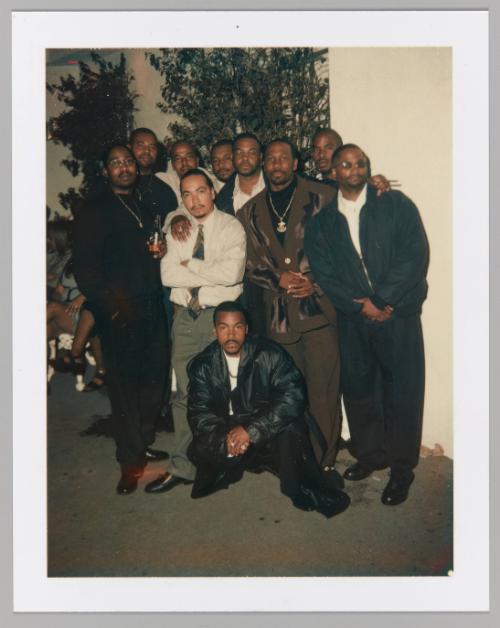 [10 men in facial hair pose for a group photograph; man in front centre kneeling with hands clasped in front]
