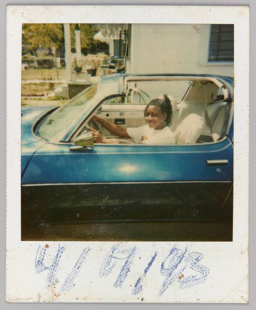 4/7/93 [Teen girl posing in driver's seat of blue convertible]