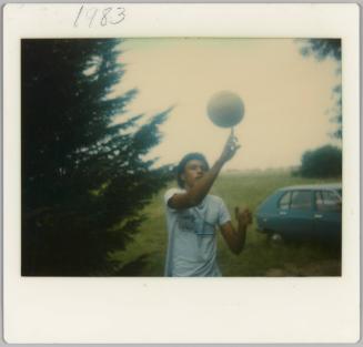 1983 [Close-up of man balancing ball on finger outside]