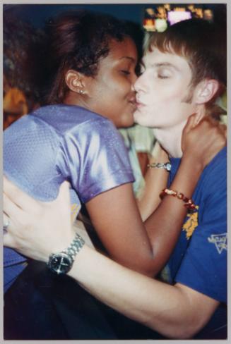 [Young man and woman dressed in purple and blue kissing on lips and holding each other]
