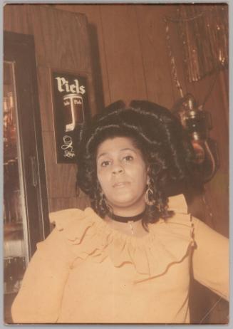 [Woman with elaborate hairpiece posing in bar]
