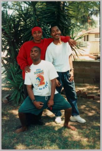 [Three young men posing in yard]
